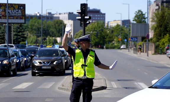 policjant ruchu drogowego stoi na skrzyżowaniu i kieruje ruchem