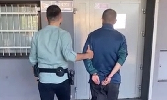 policjant z zatrzymanym mężczyzną w kajdankach