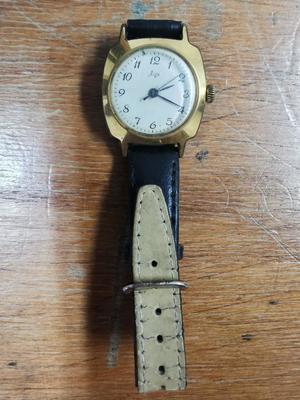 zegarek z brązową bransoletką leżacy na blacie
