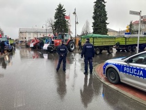 dwóch policjantów obok radiowóz, w tle ciągniki rolnicze