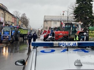 kogut policyjny radiowozu w tle ciagniki rolnicze i policjanci.