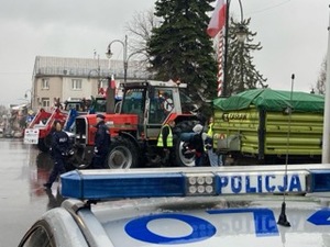 kogut policyjny radiowozu w tle ciagniki rolnicze i policjanci