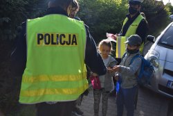 policjant stojący tyłem i dwoje dzieci odbierające odblask od policjanta