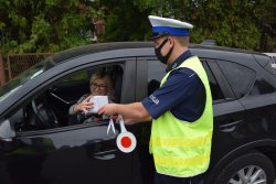 policjant przekazujący kierującej kobiecie gadżety promujące bezpieczeństwo