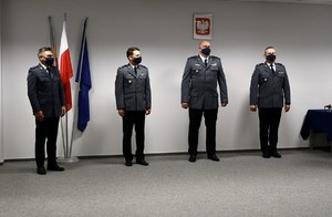 komendant powiatowy, obok jego zastęp-cy i odchodzący na emeryturę policjant, stojący podczas uroczystej zbiorki w sali odpraw KPP w Krakowie