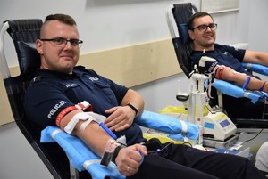dwóch policjantów siedzących na fotelach podczas oddawania krwi