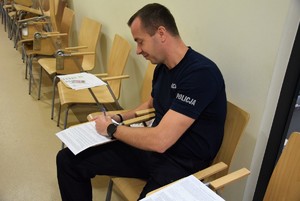 policjant siedzący na krzesle podczas wypisywania ankiety