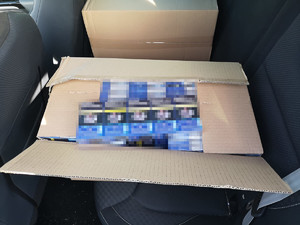 otwrate pudło kartonowe z zawartościa paczek nielegalnych papierosów, leżące na tylnym siedzeniu pojazdu