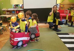 czworo dzieci w zabawkowym samochodziku, obok kucająca policjantka (2)