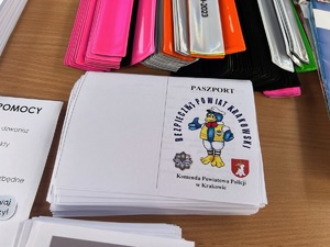 paszporty na odbitki linii papilarnych opisane Komenda Powiatowa policji w Krakowie, za nimi opaski odblaskowe