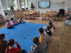 przedszkolaki siedzące na podłodze, oglądające film o bezpiecznych zachowaniach