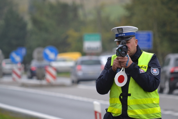 Policjant ruchu drogowego mierzy prędkość pojazdów ręcznym miernikiem