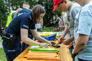 policjantka wykonująca odbitki palców chłopcu przy stoisku policyjnym na pikniku