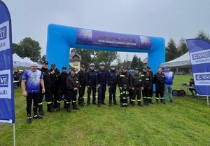 trzech umundurowanych policjantów, jeden nieumundurowany,wójt oraz strażycy OSP stojący na boisku przy balonie z napisem SMART RUN