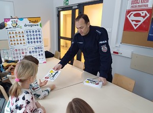 policjant rozdający dzieciom kolorowanki