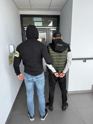 nieumundurowany policjant prowadzący zatrzymanego mężczyznę