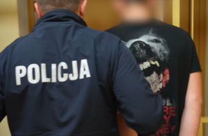 umundurowany policjant prowadzący zatrzymanego mężczyznę