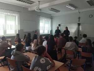 umundurowani policjanci stojący w klasie przed dziećmi