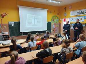 dwóch umundurowanych policjantów stojących w sali lekcyjnej przed dziećmi