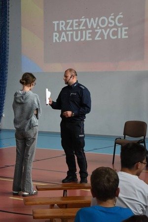 umundurowany policjant, przed nim stoi uczennica