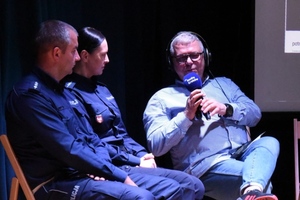 umundurowani policjanci i dziennikarz radiowy z mikrofonem