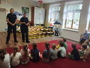 umundurowana policjantka i policjant stoją przed siedzącymi dziećmi