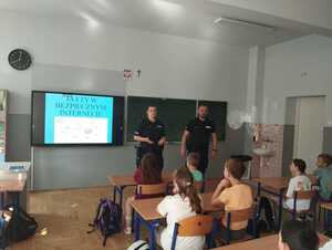 umundurowana policjantka i umundurowany policjant stoją w klasie przed dziećmi
