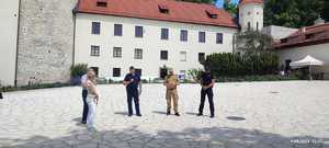 umundurowani policjanci i strażak stojący na dziedzińcu zamku