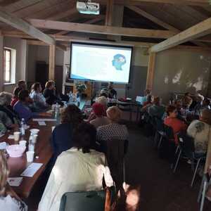 seniorzy siedzący na sali przed dzielnicowym przedstawiającym prezentację