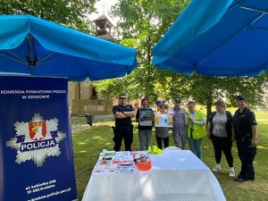 umundurowani policjanci z seniorami przy stoisku profilaktycznym