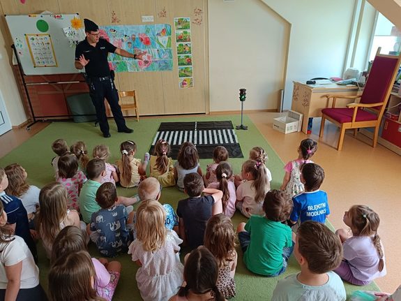 umundurowany policjant w sali przed siedzącymi dziećmi
