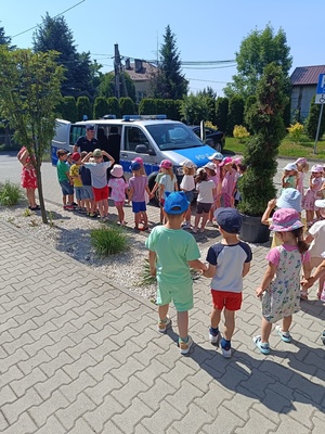 umundurowany policjnat pokazuje dzieciom radiowóz