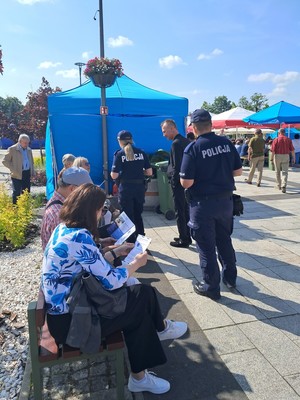 umundurowani policjanci rodają ulotki uczestnikom imprezy