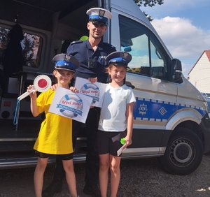 umundurowany policjant z dziećmi przed radiowozem