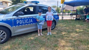 dwójka dzieci stojących przed radiowozem