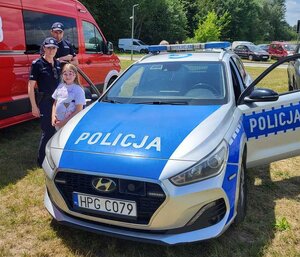 umundurowani policjanci z dziewczynką przez radiowozem