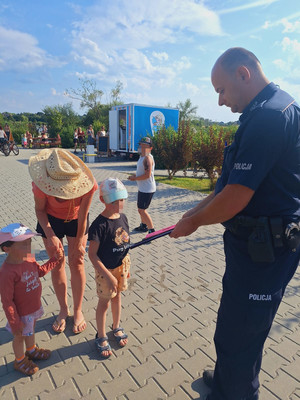 umundurowany policjant rozdaje dzieciom odblaski