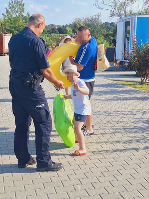 umundurowany policjant przed nim dziecko i mężczyna