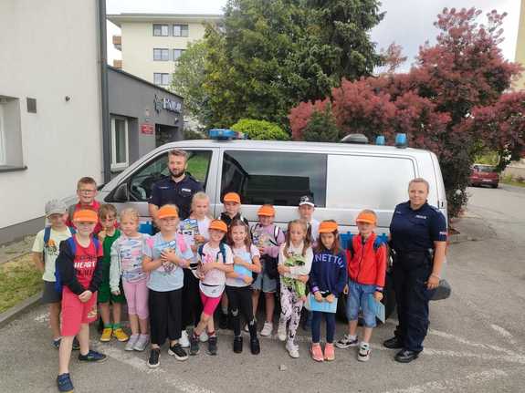 umundurowani policjanci przed radiowozem wspólnie z dziećmi pozują do grupowego zdjęcia