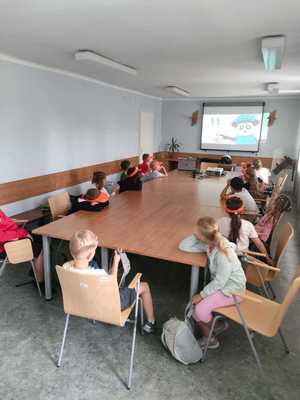 dzieci siedzą w sali w komisariacie i oglądają film edukacyjny