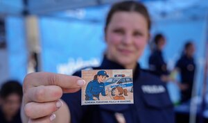 umundurowana policjantka trzyma w ręce naklejkę
