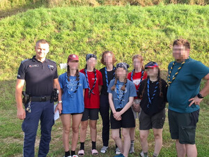 umundurowany policjant pozuje do wspólnego zdjęcia z uczestnikami obozu