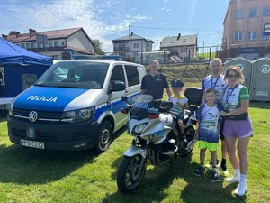umundurowany policjant z rodziną przy policyjnym motorze i radiowozie