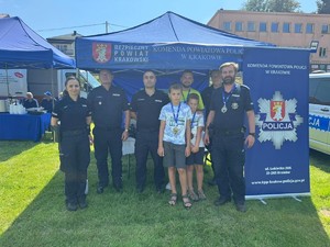 umundurowani policjanci z uczestnikami biegu przed policyjnym namiotem