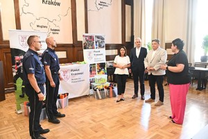 umundurowani policjanci oraz urzędnicy podczas przekazania odblasków