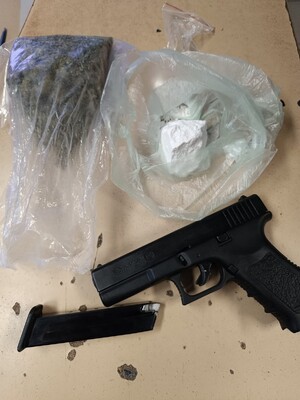 broń z magazynkiem leżąca na stole obok woreczki z zawartością środków odurzających