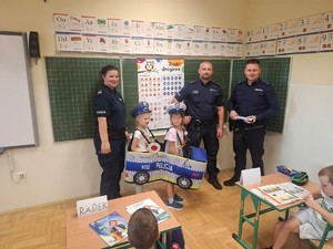 umundurowani policjanci z dziećmi w klasie przy tablicy