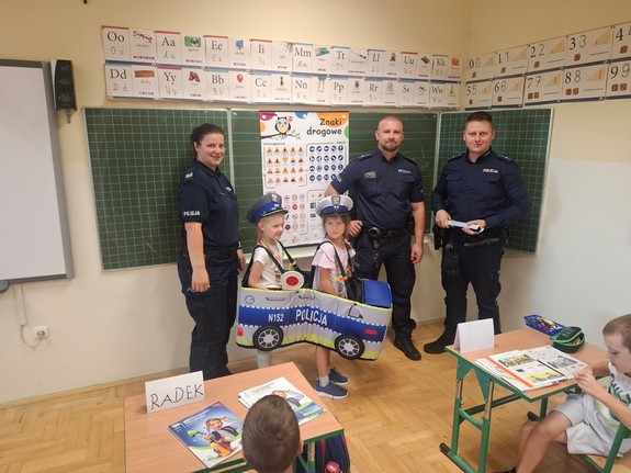 umundurowani policjanci z dziećmi w klasie przy tablicy