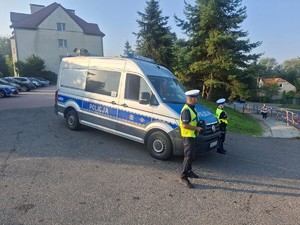 umundurowani policjanci i oznakowany radiowóz na poboczu drogi
