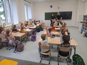 umundurowani policjanci w klasie przed nimi dzieci siedżace w ławkach
